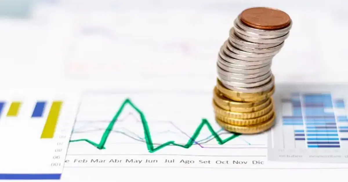 ¡Urgente! Recortar el presupuesto y frenar la politiquería en Colombia 2 Monedas apiladas sobre un gráfico financiero con curvas en descenso, símbolo de la economía colombiana y la necesidad de recortar el presupuesto.