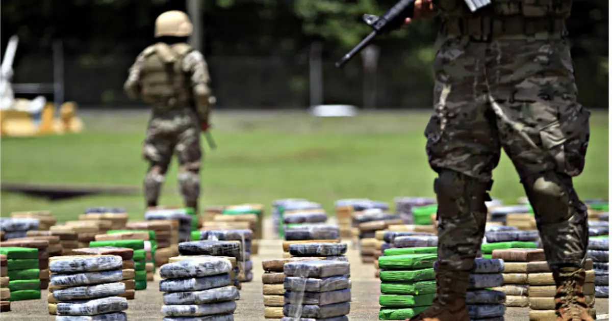 ¡Alarmante! Santos, La Violencia Y El Narcotráfico 2 Militares colombianos custodian paquetes de cocaína incautada durante una operación antinarcóticos, símbolo de la lucha contra la violencia y el narcotráfico.