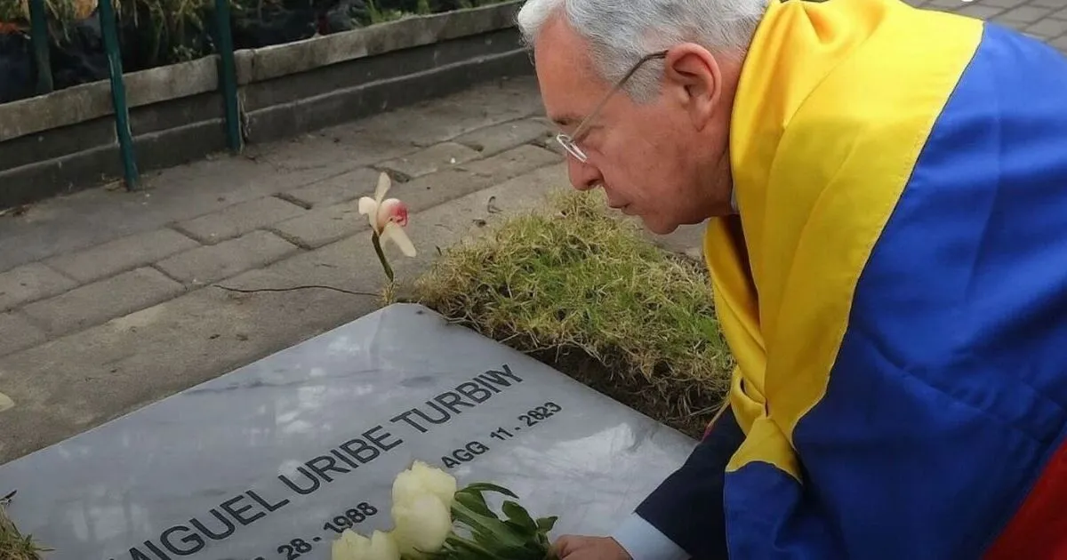 Organización británica crea el Premio Miguel Uribe Turbay: un homenaje al liderazgo joven 2 Expresidente colombiano rindiendo homenaje en la tumba de Miguel Uribe Turbay, depositando flores y envuelto en la bandera nacional, como símbolo de respeto y memoria por su legado político.