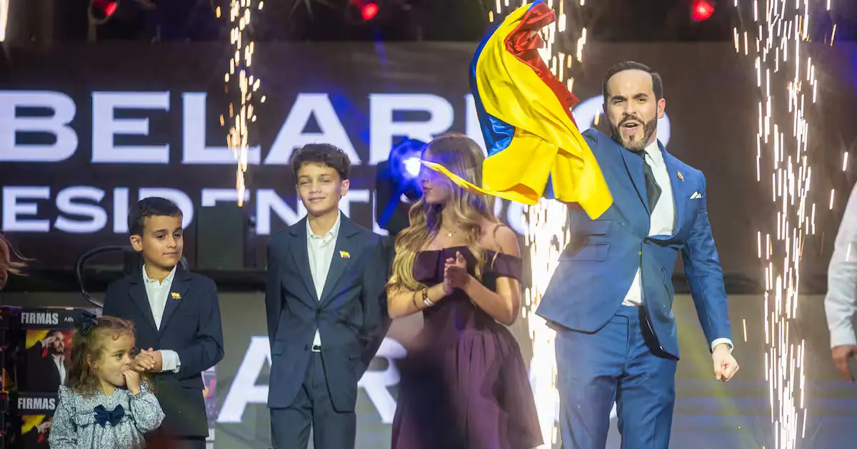 El rugido de la ESPERANZA 2 “Escena en el Movistar Arena con un candidato ondeando la bandera de Colombia junto a su familia durante un evento político, símbolo del rugido de la esperanza.”