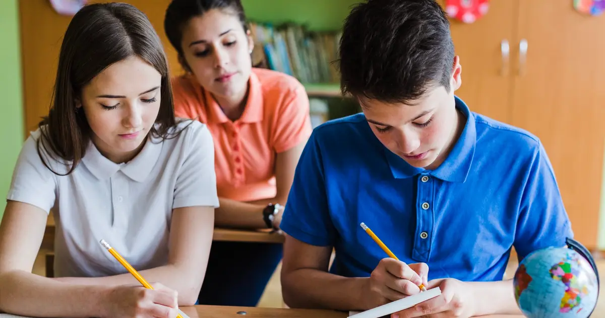 Reformar la educación, imperativo categórico del próximo Gobierno 2 Estudiantes colombianos escribiendo en clase bajo la guía de su profesora, símbolo del compromiso nacional por reformar la educación.
